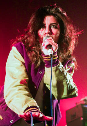 Classic Family Jewels - A young brunette woman wearing a baseball-style jacket, singing into a  microphone against