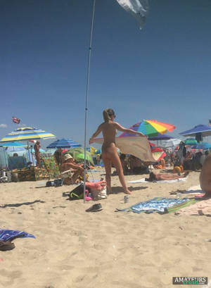candid beach ass nude - candid voyeur of teenage nudist laying her towel down on the beach