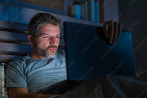 cyber sex net - man alone in bed playing cybersex using laptop computer watching porn sex  movie late at night with lascivious pervert face expression in internet  pornographic sexual content foto de Stock | Adobe Stock