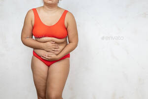 fat lady bent over nude - Naked overweight woman bending over touch stomach, white background. Woman  in red underwear with Stock Photo by burmistrovaiuliia