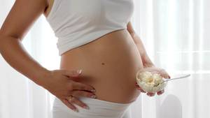 eating pregnant belly nude - future mother eats dairy products, close-up pregnant woman with big naked  tummy holds