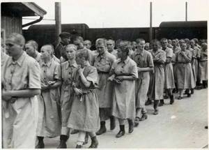 Jewish Prison Porn - Auschwitz Jewish women prisoners walk inside the women's camp, wearing the  standard prison uniform. On the left, a SS man watches them.