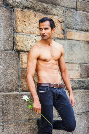 east indian american nude - Young East Indian American Man, half naked, showing strong body, wearing  black jeans, holding white rose, standing by rock wall in New York, looking  away, waiting for you.. Stock Photo | Adobe