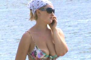 nude beach downblouse - Girl with large areola walking on the beach speaking on the phone
