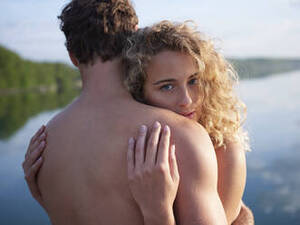 natural nudist couples beach - Nude couple embracing in nature, woman looking at camera stock photo