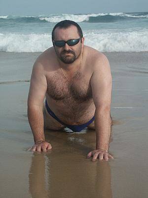 fat hairy nudist gallery - Fat hairy chested bear in shades poses nude in wet sand on the wild beach