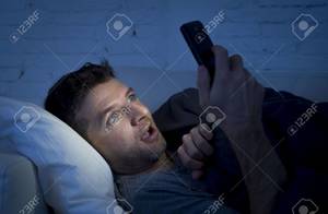 Home Porn Youngest - young man in bed couch at home late at night with intense face expression  using mobile