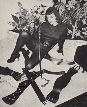 50s Bdsm Porn - Woman in black tight clothing surrounded by leather belts and straps