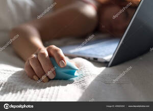 Girl Computer Watching Porn - A woman lies in bed holding a clitoral vibrator and watching porn on a  laptop. The girl has sex online Stock Photo by Â©inside-studio 495925262