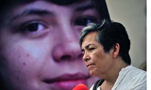 indians raid ranchers wife fuck - a woman protesting in front of an image of her child