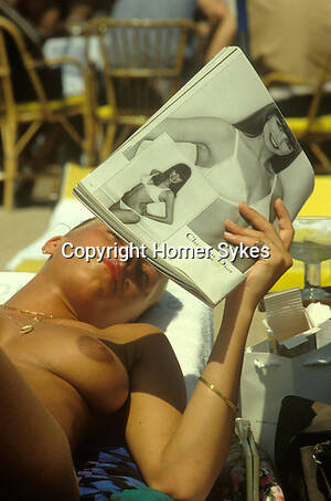 cannes beach topless - cannes film festival topless woman on beach reading magazine | HOMER SYKES