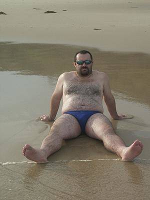 fat hairy nudist gallery - Fat hairy chested bear in shades poses nude in wet sand on the wild beach