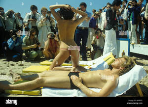 homemade nude beach videos - Cannes Film Festival semi nude woman topless on beach with boyfriend. Pose  amateur and press photographers at work working. 1980s France HOMER SYKES  Stock Photo - Alamy