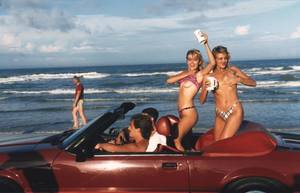 College Spring Break Car - Women drink and dance topless in an open-top car in Daytona Beach during the