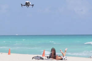 drone voyeur cam beach - A drone filming a sunbather on a beach