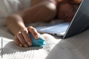 Girls Watching Porn On Computer - A woman lies in bed holding a clitoral vibrator and watching porn on a  laptop. The girl has sex online Stock Photo | Adobe Stock