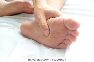 massage techniques for foot pain - Foot Pain ,young man sitting on the bed at home, he holding feet press