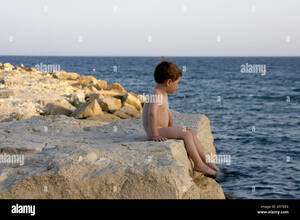 group nudism galleries - Young boy naked nude or bare sitting on rocks by the sea in Cyprus Stock  Photo - Alamy