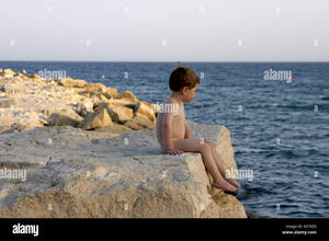 naked nudist gallery - Young boy naked nude or bare sitting on rocks by the sea in Cyprus Stock  Photo - Alamy